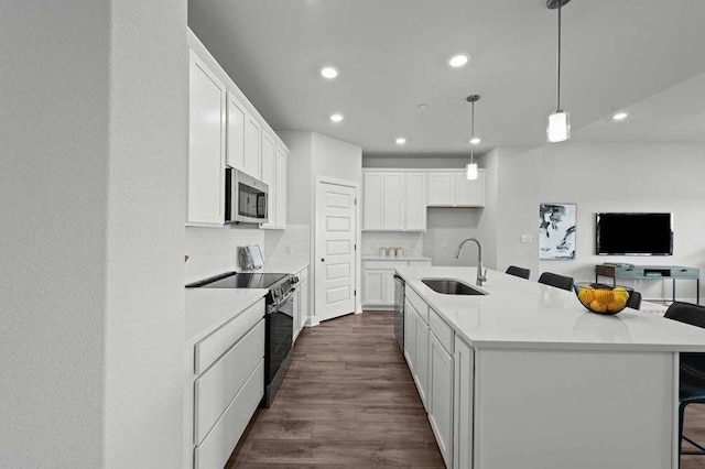 kitchen featuring sink, appliances with stainless steel finishes, hanging light fixtures, an island with sink, and white cabinets