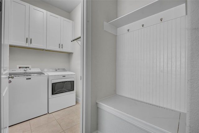 washroom featuring cabinets, washing machine and dryer, and light tile patterned floors