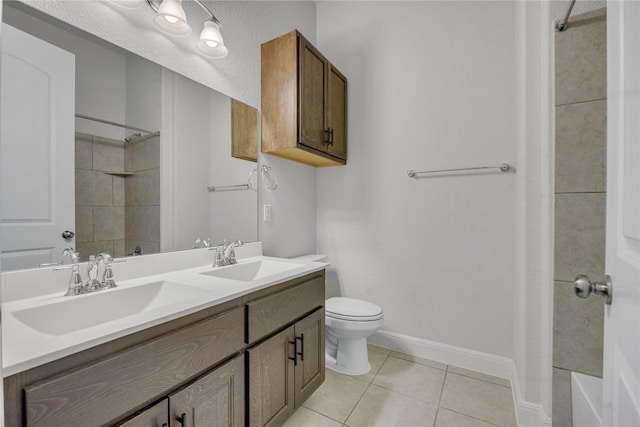 bathroom with tile patterned flooring, vanity, tiled shower, and toilet