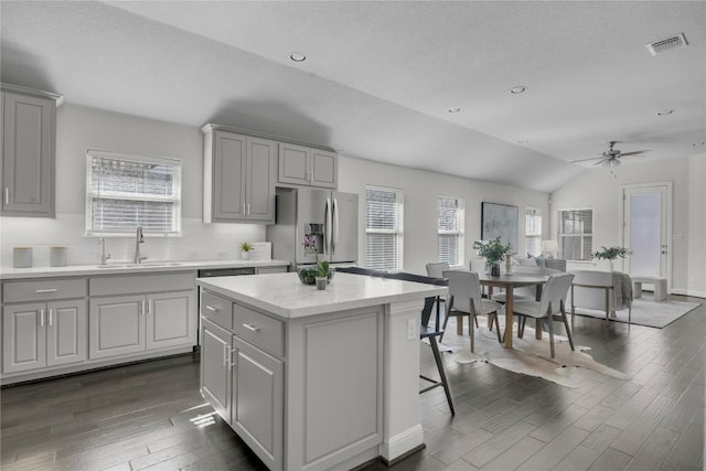 kitchen featuring sink, dark wood-type flooring, a center island, tasteful backsplash, and stainless steel fridge with ice dispenser