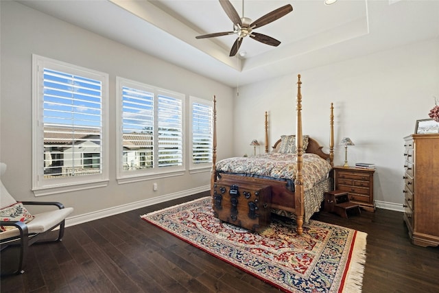 bedroom with dark hardwood / wood-style flooring, a tray ceiling, and ceiling fan