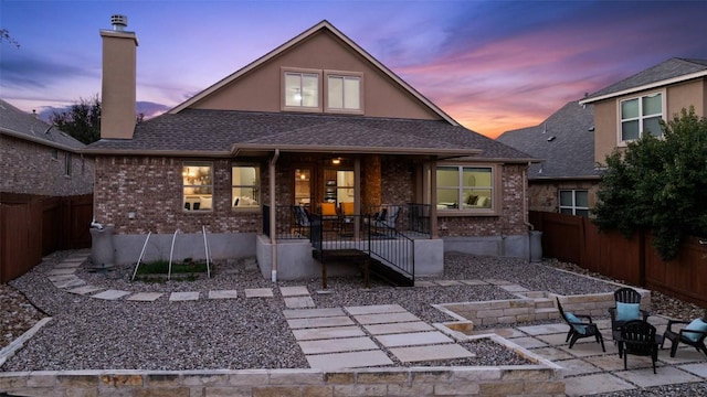 back house at dusk featuring a patio area and an outdoor fire pit