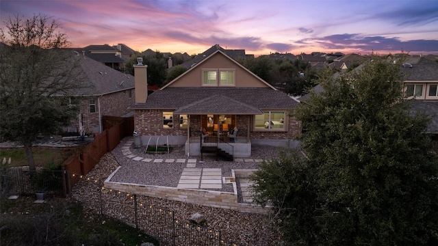 back house at dusk featuring a patio area