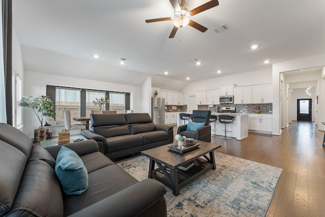 living room with ceiling fan, vaulted ceiling, and wood-type flooring