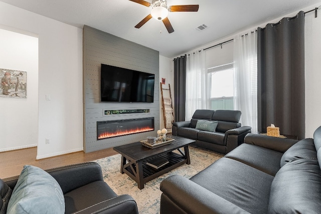 living room with a large fireplace and ceiling fan