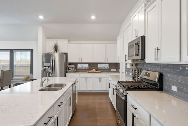 kitchen featuring sink, light stone counters, tasteful backsplash, appliances with stainless steel finishes, and white cabinets