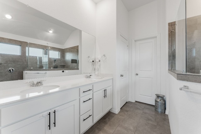 bathroom featuring vanity, vaulted ceiling, tiled shower, and tile patterned floors