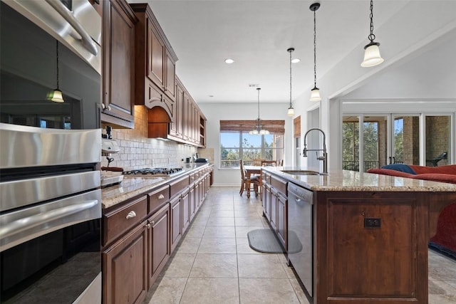 kitchen featuring pendant lighting, sink, stainless steel appliances, and a center island with sink