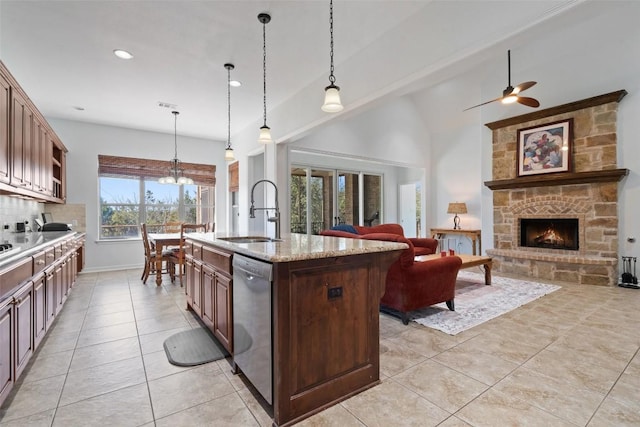 kitchen featuring sink, hanging light fixtures, light stone countertops, an island with sink, and stainless steel dishwasher