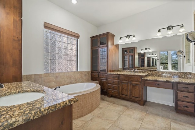 bathroom featuring a relaxing tiled tub, vanity, and tile patterned flooring