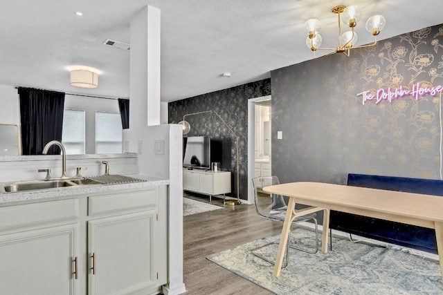 kitchen with white cabinetry, sink, an inviting chandelier, and light wood-type flooring