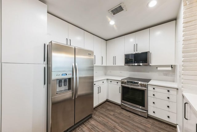 kitchen with white cabinetry, decorative backsplash, dark wood-type flooring, and stainless steel appliances