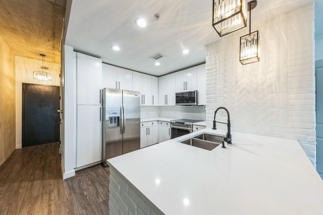 kitchen with appliances with stainless steel finishes, pendant lighting, white cabinetry, sink, and kitchen peninsula