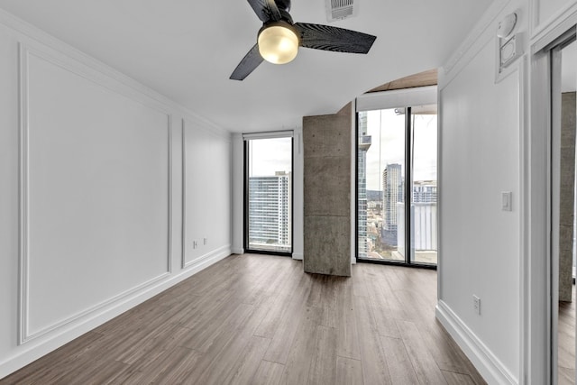 unfurnished room with ceiling fan, a wall of windows, and hardwood / wood-style flooring