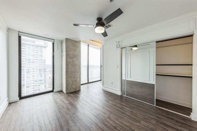 unfurnished bedroom featuring dark hardwood / wood-style flooring, a closet, floor to ceiling windows, and ceiling fan