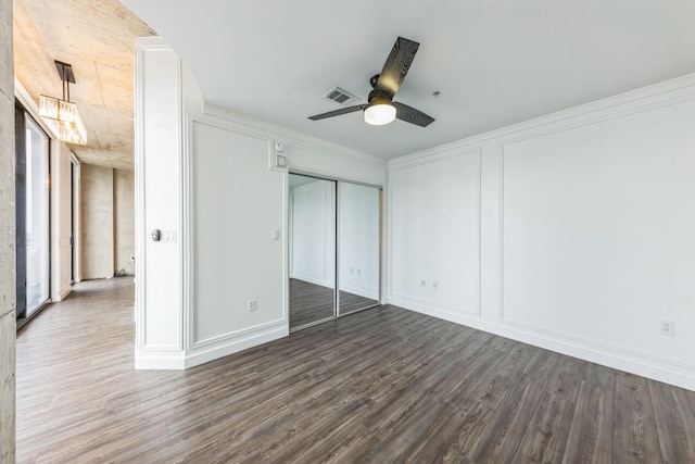 unfurnished bedroom featuring crown molding, dark wood-type flooring, ceiling fan, and a closet