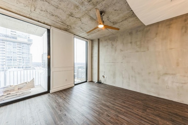 spare room featuring hardwood / wood-style flooring, a wall of windows, and ceiling fan