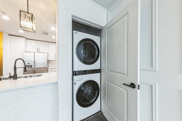 laundry area featuring stacked washer and dryer and sink