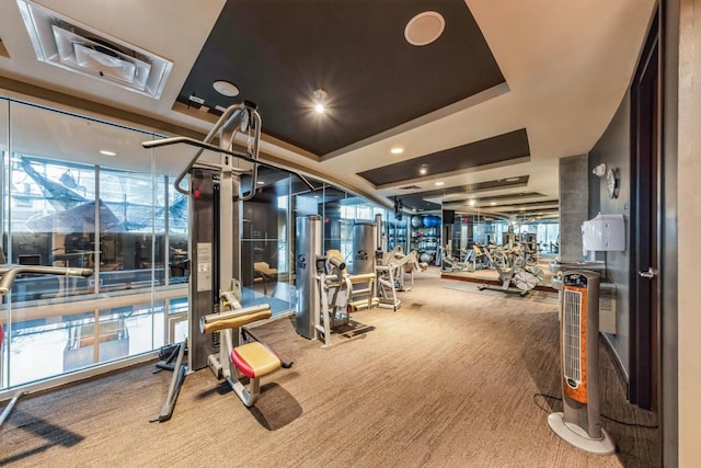 workout area featuring a raised ceiling and carpet flooring