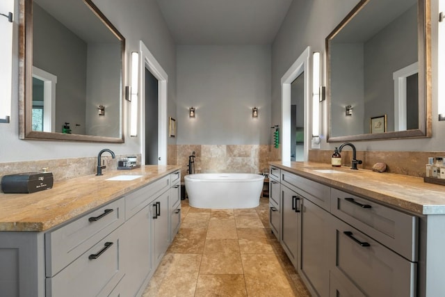 full bath with a freestanding bath, two vanities, and a sink