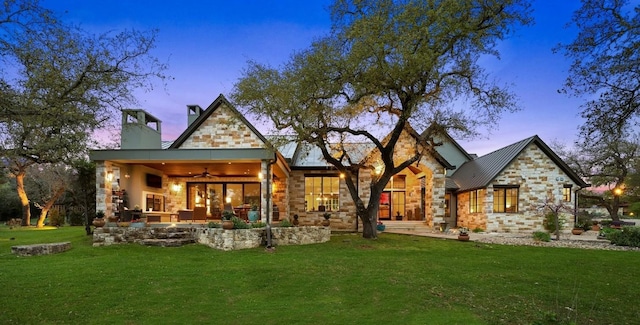 back house at dusk featuring a patio, a yard, and ceiling fan