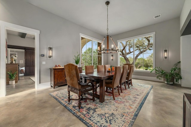 dining room featuring concrete flooring, visible vents, a notable chandelier, and a barn door