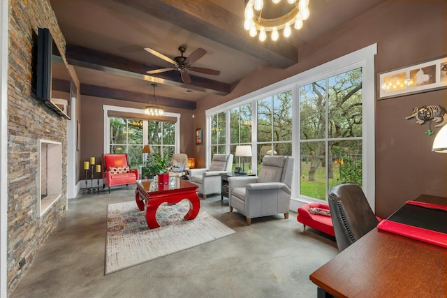 sunroom with ceiling fan with notable chandelier, a stone fireplace, and beamed ceiling