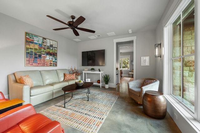 living room with finished concrete floors, visible vents, baseboards, and a ceiling fan