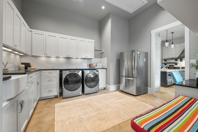 clothes washing area featuring washing machine and clothes dryer, recessed lighting, a high ceiling, a sink, and baseboards