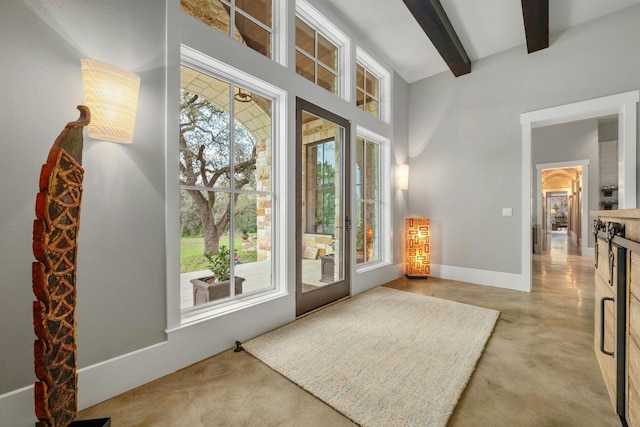 doorway with a healthy amount of sunlight, a high ceiling, baseboards, and beamed ceiling