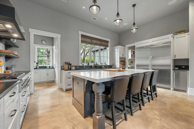 kitchen with appliances with stainless steel finishes, finished concrete floors, visible vents, and wall chimney exhaust hood