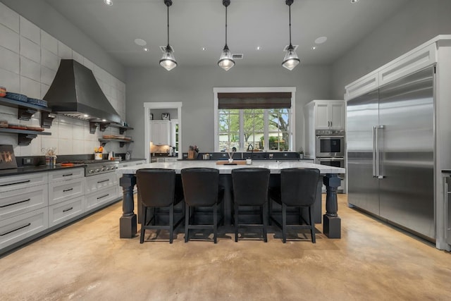 kitchen featuring a breakfast bar area, open shelves, stainless steel appliances, decorative backsplash, and wall chimney exhaust hood