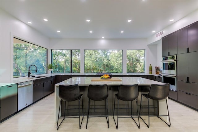 kitchen featuring stainless steel appliances, sink, a kitchen breakfast bar, and a large island