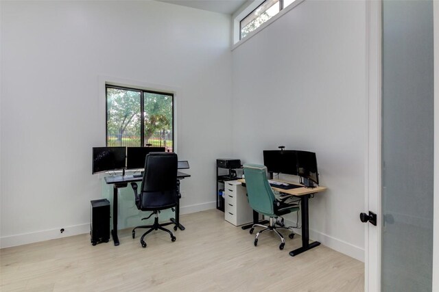 office area with a towering ceiling and light wood-type flooring