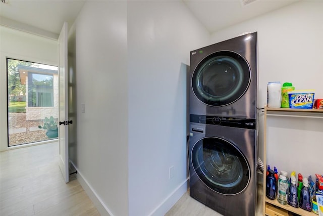 clothes washing area featuring stacked washer / drying machine and light hardwood / wood-style flooring