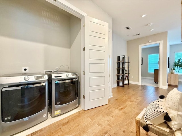 clothes washing area featuring washing machine and dryer and light hardwood / wood-style flooring