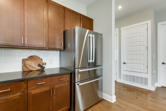 kitchen with tasteful backsplash, stainless steel fridge, and light hardwood / wood-style floors