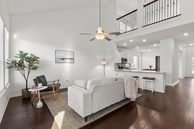 living room with ceiling fan, dark hardwood / wood-style floors, and a high ceiling