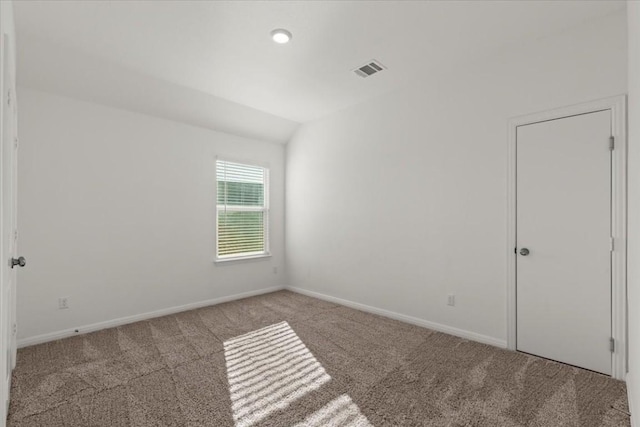 carpeted spare room with lofted ceiling