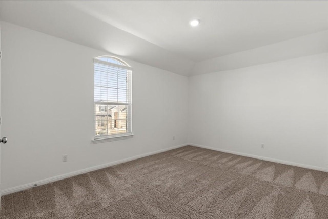 carpeted empty room with vaulted ceiling