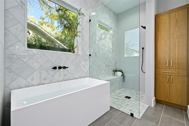 bathroom with tile patterned floors, separate shower and tub, and tile walls