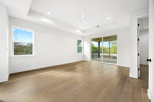 unfurnished room with wood-type flooring, a raised ceiling, and ceiling fan