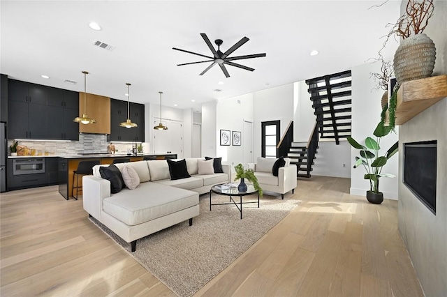 living room with sink, light hardwood / wood-style floors, and ceiling fan