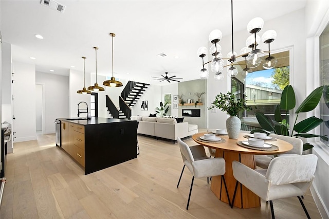 kitchen featuring light hardwood / wood-style flooring, sink, a center island with sink, and decorative light fixtures