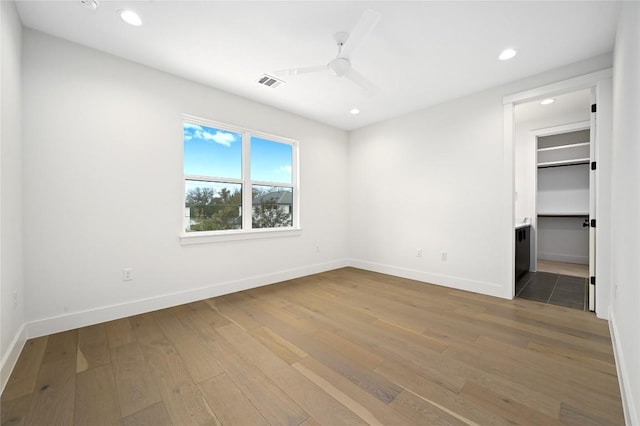 unfurnished bedroom with ceiling fan, a spacious closet, and light hardwood / wood-style flooring