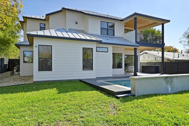 back of property featuring a balcony and a lawn