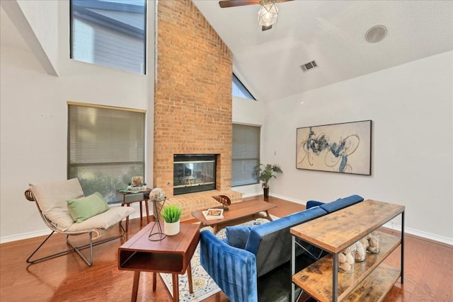 living room featuring wood-type flooring, high vaulted ceiling, ceiling fan, and a fireplace