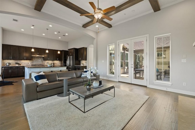 living room featuring a high ceiling, light wood-type flooring, and beam ceiling