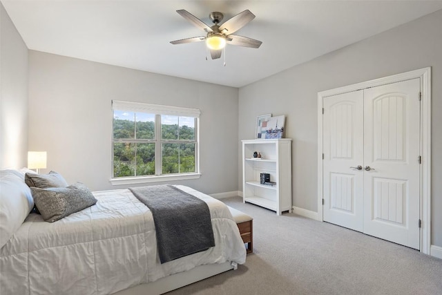 bedroom featuring light colored carpet, ceiling fan, and a closet