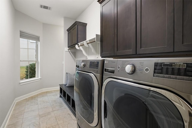 clothes washing area with cabinets and separate washer and dryer